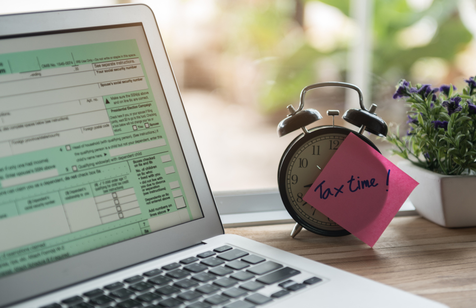 tax time post-it on alarm clock and Individual income tax return form online.